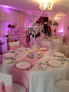 a table set up with white and pink linens for a formal dinner or party