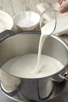 a person pouring milk into a pot on a table