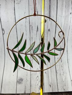 a metal tree with green leaves hanging from it's side on a wooden table