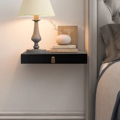 a nightstand with a lamp on top of it next to a bed