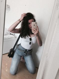 a woman taking a selfie in front of a mirror with her hand on her hip