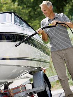 an older man is washing his boat with a high pressure washer while standing next to it