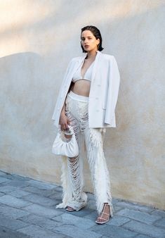 a woman in white outfit standing next to a wall