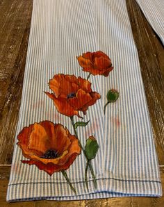 three orange flowers on a blue and white striped towel