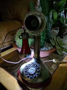 an old fashioned phone sitting on top of a wooden table next to potted plants