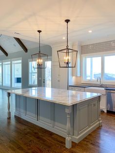 a large kitchen with an island in the middle and two pendant lights hanging from the ceiling