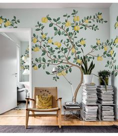 a tree with lemons painted on the wall next to a chair and bookshelf