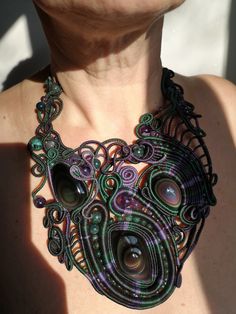 a close up of a woman wearing a necklace made out of wire and glass beads