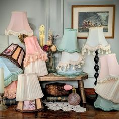 several lamps are sitting on a table in front of pictures and other decorative items,