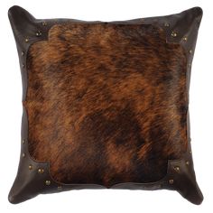 a brown and black cowhide pillow with studdings on the front, sitting on a white background