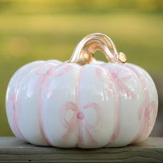 a white and pink painted pumpkin sitting on top of a wooden table with grass in the background