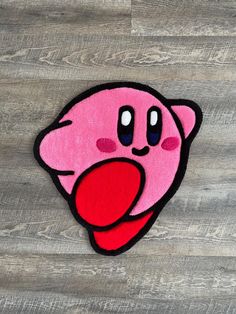 a pink rug with a red tongue sticking out of it's mouth on top of a wooden floor