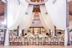 an indoor wedding reception with white draping and floral centerpieces