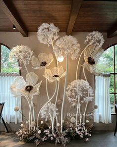 an arrangement of white flowers on display in front of a window with curtains and windowsills