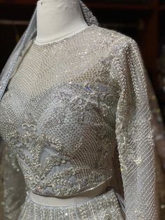 Cloudy grey intricate with fully sequence, studs motifs thread embroidery and crystal stone work lehenga embellished with pearl design paired with high neck blouse and net dupatta. Fabric: Net Custom designed according to client measurements and color preference. Production and delivery time is 120 days! Silver Party Dress With Intricate Embroidery, Silver Party Wear Sets With Intricate Embroidery, Silver Party Wear Lehenga With Intricate Embroidery, Silver Hand Embellished Lehenga For Wedding, Silver Lehenga With Intricate Embroidery For Party, Silver Hand Embellished Festive Gown, Silver Hand Embellished Wedding Lehenga, Silver Hand-embellished Festive Gown, Wedding Silver Hand Embellished Lehenga