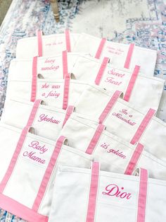 pink and white personalized tote bags sitting on top of a blue table cloth