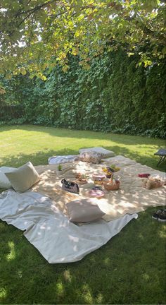 an outdoor picnic is set up in the shade with food and drinks laid out on it