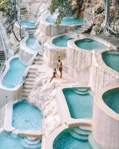 a man and his dog are standing in front of the blue water pools at an outdoor swimming pool