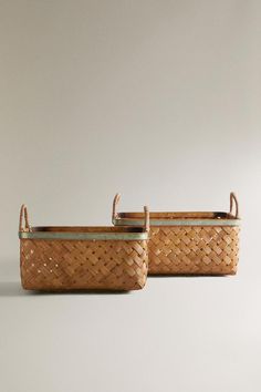 two woven baskets sitting side by side on top of a white surface, one with handles and the other without handles