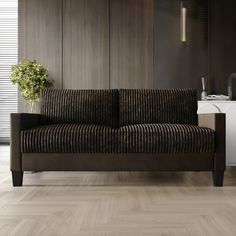 a brown couch sitting on top of a hard wood floor next to a white sink