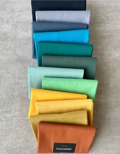 six different colors of fabric stacked on top of each other in a row, with one folded