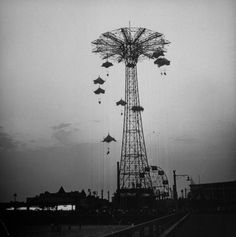 a black and white photo of an amusement park ride with flying birds in the sky