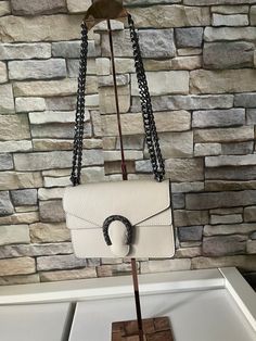 Real leather bag made in Italy. Beautiful beige bag, with black colored edges, has a "horseshoe" decorative element. Magnetic closure, internal pocket with belt. Shoulder strap in the shape of the chain made of black metal, can be adjusted as desired, as seen in the photo. Measurements: 20x15x6 cm. New with tags: A new, unused and unworn item in its original packaging (box or bag) and/or with original tags attached. Made in Italy. With each bag we give you a dustproof case. Rectangular Shoulder Bag With Horsebit Detail For Everyday Use, Rectangular Bags With Horsebit Detail For Everyday Use, Beige Leather Shoulder Bag With Silver-tone Hardware, Everyday Crossbody Bag With Horsebit Detail, Beige Leather Shoulder Bag With Palladium Hardware, Everyday Crossbody Shoulder Bag With Horsebit Detail, Rectangular Leather Bag With Horsebit Detail, Beige Rectangular Shoulder Bag With Horsebit Detail, Beige Leather Shoulder Bag With Horsebit Detail