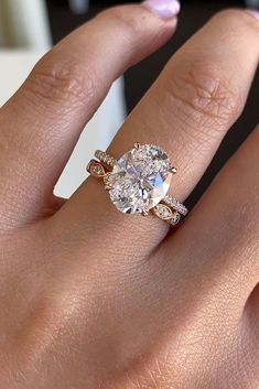 a woman's hand with a ring on her finger and an oval shaped diamond in the middle