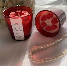 a red candle next to a pearl necklace