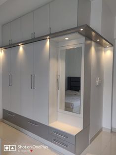 an empty bedroom with mirrored closets and white cabinets in the corner, all lit up by recessed lights