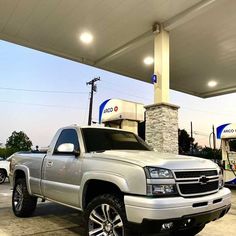 a silver truck parked in front of a gas station