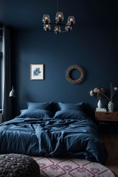 a bedroom with dark blue walls and wooden flooring, a chandelier above the bed