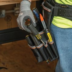 a person holding several tools in their belt and wearing gloves with them on his arm