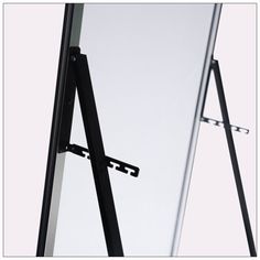 a black and white photo of an easel leaning against a wall with its reflection in the mirror