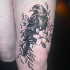 a black bird sitting on top of a branch with flowers