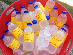 plastic bottles filled with water sitting on top of a red bucket full of baseballs