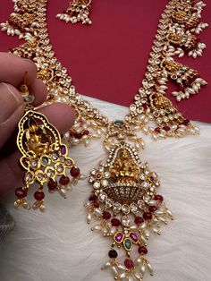 Goddess Lakshmi CZ Color Stone Rice Pearls Guttapusalu Necklace with matching earringsColor : GoldenSize : Necklace Length : 24 Inches; Earring Length : 2 Inches ApproxStones : CZ Red Green Stone Pearls Red Kundan Necklace With Latkans For Navratri, Red Kundan Necklace For Diwali Rituals, Red Necklace With Zari Work For Puja, Red Kundan Necklace For Navratri, Red Kundan Necklace For Navratri Celebration, Festive Red Kundan Necklace With Latkans, Red Bollywood Kundan Necklace For Rituals, Red Bridal Necklace With Latkans For Diwali, Heavy Red Temple Necklace For Festive Occasions