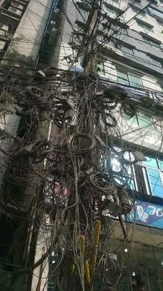 wires are tangled up on the side of a building in front of a tall building