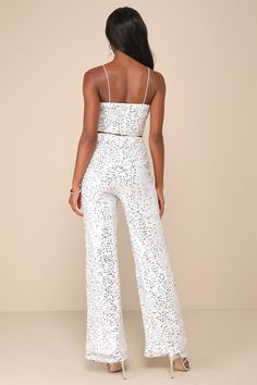 Your style already has a shining reputation, and the Lulus Sparkling Image White Sequin Two-Piece Jumpsuit is just here to remind everyone! Glittering silver sequins and silver lurex threading adorn loose mesh as it shapes this two-piece set that features a cropped, V-neck tank top with slender spaghetti straps. The matching bottoms have a high waist (with elastic at the back) that tops relaxed, straight pant legs that end at ankle-length hems. Both the top and the bottoms have hidden back zippers. Fit: This garment fits true to size. Length: Floor length. Size medium Bust: Great for any cup size. Waist: Fitted - very fitted at natural waist. Hip: Loosely Fitted. Undergarments: May be worn with a strapless bra, adhesive bra, petals, or no bra. Fabric: Fabric is very stretchy. Lined. Shell: V Neck Jumpsuit Outfit, White Sequined Party Bottoms, Glamorous White Party Bottoms, White Sequined Bottoms For A Night Out, White Disco Outfit, White Sequin Jumpsuit, Shiny Jumpsuit, Silver Jumpsuits, Glitter Jumpsuit