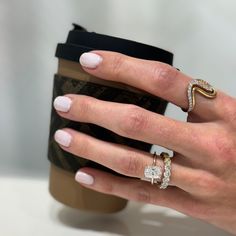 a woman's hand holding a coffee cup with two rings on it