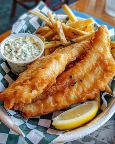 fish and fries on a plate with dipping sauce