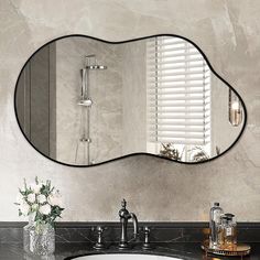 a bathroom sink sitting under a large mirror next to a vase with flowers on it