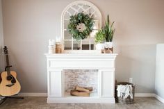 a living room with a fireplace and a wreath on the mantle next to a guitar