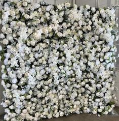 a bunch of white flowers are arranged on a wall in the shape of a square