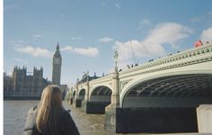 a woman standing in front of a bridge with big ben in the background