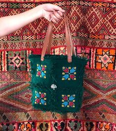 this handbag makes your style more unique and special because it's handmade 100% with much love... I made it with my mom by using  hand-woven tissue by the women of Artissma Foundation which means :"Art du Tissage Marocain".  PS: (Don't forget to check our story) https://www.etsy.com/your/shops/artissma/tools/listings So, this bag is made by woolen threads with shoulder straps made by genuine leather, and decorated by different Berber symbols inspired by nature and Moroccan culture, with some si Handmade Rectangular Festival Bag, Artisan Tote Bag For Festival, Bohemian Handheld Bag With Leather Handles, Bohemian Handheld Bags With Leather Handles, Artisan Festival Tote Bag, Green Bohemian Crochet Bag For Market, Handmade Tote Bag For Festivals, Green Bohemian Handheld Bag, Bohemian Green Leather Bags