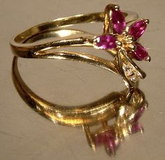 A 10k rubies and diamonds flower ring circa 1970s. This vintage size 7 yellow gold ring has four marquise cut claw-set genuine rubies and a pair of two point genuine diamonds.  Resembling an abstract lily, the top of the ring measures 1/2" across the setting and it weighs 2.5 grams.  It is marked 10K.  It is in excellent vintage condition with no chips, cracks, dents, bends, corrosion, losses, damage or known repairs.  Jewelry will have signs of use. Expedited parcel to the U.S. starts at $22.00 and expedited parcel within Canada starts at $17.00 (tracking and loss insurance is included).  At this time, we are required to choose a single postal rate, which may not be applicable to your location, or if you require a more expensive option. If your quote is significantly different, we will se Vintage Flower-shaped Multi-stone Jewelry, Vintage Ruby Jewelry With Diamond Accents, Vintage Flower Shaped Diamond Ring, Vintage Flower-shaped Gemstone Jewelry, Vintage Flower Gemstone Jewelry, Vintage Diamond Ruby Ring, Vintage Marquise Jewelry With Prong Setting, Vintage Multi-stone Marquise Cut Jewelry, Vintage Marquise Cut Multi-stone Jewelry