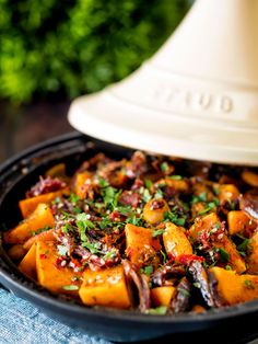 sweet potato with dates and almonds in a skillet next to a white lamp