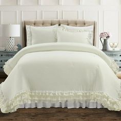 a white bed with ruffled edges and pillows