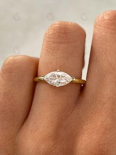 a woman's hand with a diamond ring on top of her finger, showing the side view